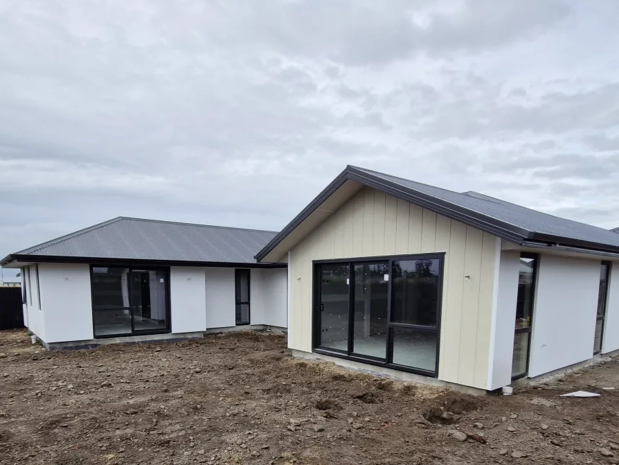 Single-storey new build with white render and board-and-batten gable feature