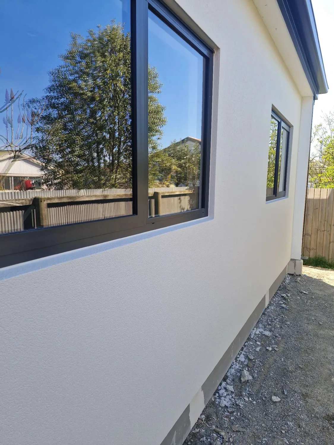Smooth white render on a home's side elevation with dark joinery